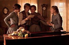 three women standing in front of a wooden desk