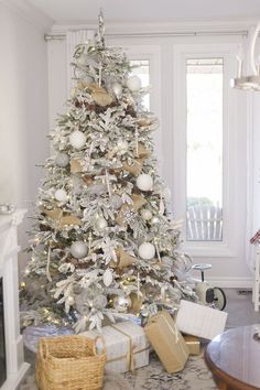 a white christmas tree with gold and silver ornaments in a living room decorated for the holidays