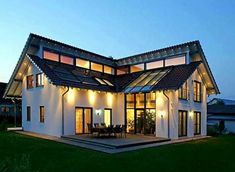 a house that is lit up at night with lights on the roof and patio area