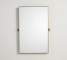 a mirror mounted to the side of a wall next to a white wall with a gold frame