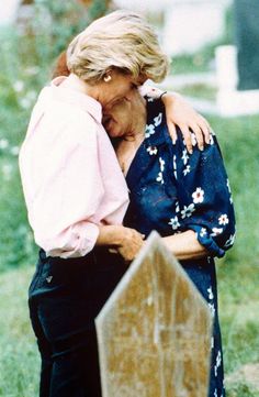 two women embracing each other in front of a grave