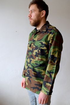 "Camouflage jacket, hunting shirt, military shirt, army topcoat, olive greet, outdoor jacket, outwear, men khaki green, women oversized, M/L Military camouflage button-up jacket. Jacket has two chest pockets. Authentic military in excellent condition. Size: seems like men (M) and women (L) Measurements: Length: 78 cm/ 31\" Shoulder to shoulder: 49 cm/ 19\" Sleeve: 60 cm/ 24\" Bust: 114 cm/ 45\" Condition: excellent Brand: authentic military Fabric: polyester, cotton * Wash at temperature not hig Long Sleeve Camouflage Windbreaker With Pockets, Military Style Green Cotton Windbreaker, Camouflage Long Sleeve Utility Jacket For Outdoor, Green Long Sleeve Utility Jacket For Hunting, Green Hunting Utility Jacket For Fall, Green Utility Jacket For Hunting In Fall, Combat Style Khaki Long Sleeve Windbreaker, Green Combat Cotton Outerwear, Green Utility Jacket For Fall Hunting