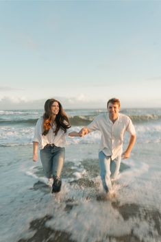 a man and woman are running in the water at the beach holding each other's hands