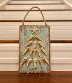 a wooden sign with shells in the shape of a christmas tree hanging on a wall