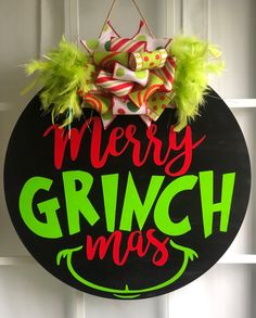 a merry grinmas sign hanging on the front door with green and red decorations around it