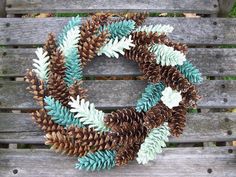 a wreath made out of pine cones sitting on top of a wooden bench