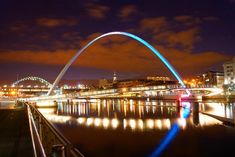 the st louis arch lit up at night with lights reflecting in the water and onlookers