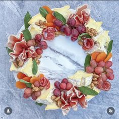 a cake decorated with fruit and nuts on top of a marble slab topped with leaves