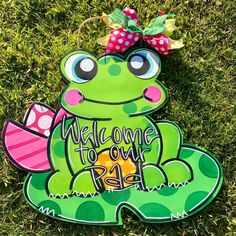 a green frog with a bow on it's head is sitting in the grass