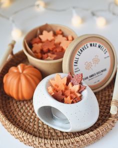 two small bowls filled with fall leaves next to a candle