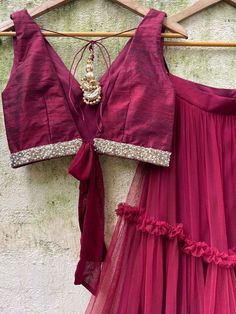 A three-piece burgundy tier ruffle lehenga set from the Priti Sahni collection. This raw silk burgundy ruffle tier lehenga is paired with a deep neck burgundy blouse in raw silk fabric with sequin-pearl detail. The lehenga has side hanging tassels to the waistline. And the blouse has a ghungroo tassel and ribbon tie-up at the back. The outfit is completed with a burgundy sequined butti work net dupatta with scalloped edging. Off Shoulder Lehenga, Tiered Lehenga, Ruffle Lehenga, Raw Silk Blouse, Net Blouse, Raw Silk Lehenga, Yellow Lehenga, Pearl Work, Ivory Blouse