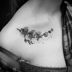 a black and white photo of a woman's chest with an orchid tattoo on it