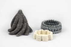 three knitted objects sitting next to each other on a white surface, one is gray and the other is grey