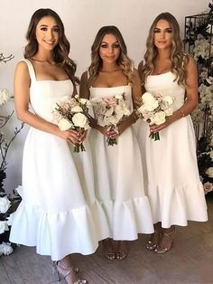 three women in white dresses standing next to each other with flowers on their bouquets