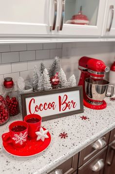 a kitchen counter topped with red cups and saucers next to a sign that says cocoa bar