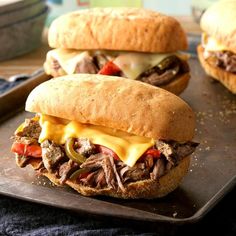 two sandwiches with meat, cheese and peppers on a tray