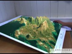 a person is holding up a large map with mountains on it and water in the middle