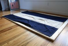 a large blue and white blanket laying on top of a hard wood floor in an empty room