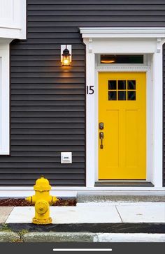 a yellow fire hydrant in front of a gray house with white trim and windows