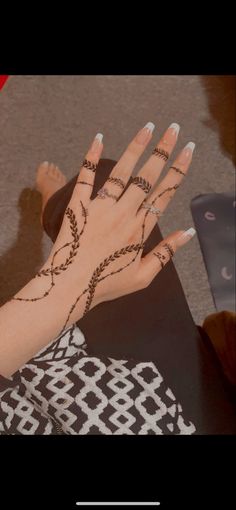 a woman's hand with henna tattoos on it