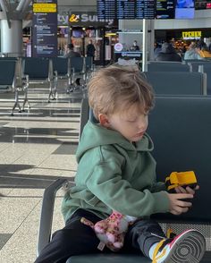 a little boy sitting on top of a chair at an airport