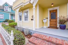 a yellow house with red brick steps leading up to the front door