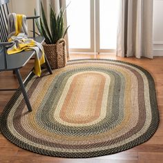 a round rug is on the floor next to a chair and potted plant in front of a window