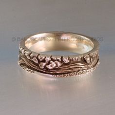 this is an image of a wedding ring with flowers and leaves on the band in gold