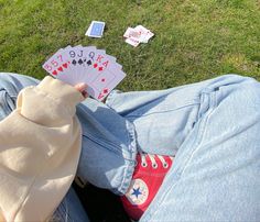 a person sitting in the grass with some playing cards