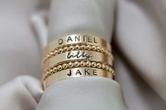 Create your own beautiful set of name rings to show off the people closest to your heart! So simply pretty! Our 3mm high quality 14k Gold-Filled band rings fit one date, name or word in your choice of font. Our rings stack beautifully together, so purchase up to 3 name band rings total for one finger. Please keep the total characters per ring to around 20 max. Up to 3 name ring bands with two spacers will fit on one finger, and we recommend sizing to the next whole size up if you are stacking 3 rings. Please read the sizing details first in the DETAILS section below. D E T A I L S 14k Gold Filled Name Band Rings: Whole US Sizes: 4 - 10 Option to add spacer rings Lowercase tiny script font or UPPERCASE Arial Choose natural or darkened lettering Fit one name, date or word per ring Stamped by Engraved Rings For Women Names, Trendy Rings For Women, Stackable Rings For Each Child, Custom Name 14k Gold Stackable Rings For Anniversary, Custom Name Stackable Rings In 14k Gold For Anniversary, 14k Gold Stackable Rings With Custom Name For Anniversary, Personalized Stackable 14k Gold Rings, Classic Jewelry With Custom Text For Anniversary, Custom Name Stackable 14k Gold Rings For Wedding