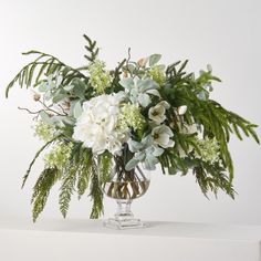 a vase filled with white flowers and greenery