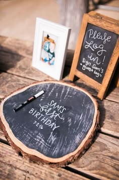 a wooden table topped with a chalkboard and two framed pictures next to each other