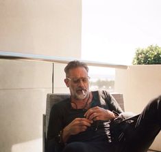 a man sitting in a chair looking at his cell phone