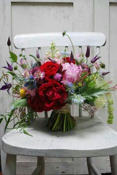 a bouquet of flowers sitting on top of a white chair next to a wooden door