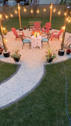 an outdoor dining area with chairs, lights and gravel path leading to the back yard