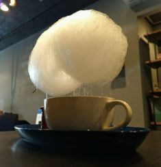 a cup with some sugar on top of it and a ball of cotton in the middle