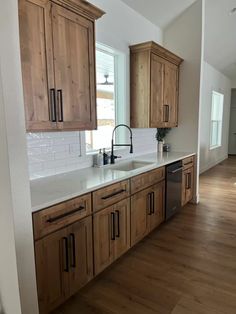 an empty kitchen with wooden cabinets and white counter tops, wood flooring and stainless steel appliances