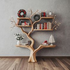 a wooden tree shelf with books and wreaths on it in front of a gray wall