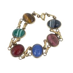 This vintage 12k Gold Filled bracelet features a stunning assortment of oval cabochon gemstones, including Tiger's Eye, Malachite, Lapis Lazuli, and more, all set in gold-tone links. Each stone is unique, contributing to the piece's timeless elegance. Its secure clasp ensures it stays in place, making it a versatile addition to any jewelry collection. * Gold-tone metal * Oval cabochon gemstones * Tiger's Eye, Malachite, Lapis Lazuli, and more * Secure clasp * Vintage design Minor tarnish on metal links Features: * Gold Filled Size: Womens 7&1/2" Condition: Pre-Owned Good Multi Gemstone Bracelet, Place Making, Tiger's Eye, Oval Cabochon, Gemstone Bracelet, Chain Link Bracelet, Gold Tone Metal, Lapis Lazuli, Womens Jewelry Bracelets