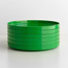 a stack of green plates sitting on top of a white table next to each other