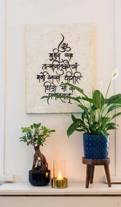 two potted plants sit on a mantle in front of a painting and candle holder