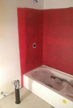 a bathtub with red paint on the walls in a bathroom that is under construction