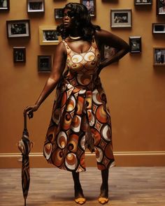 a woman holding an umbrella standing in front of a wall with pictures on the walls