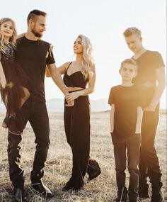 a group of people standing next to each other on top of a dry grass field