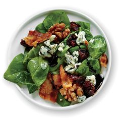 spinach salad with bacon, blue cheese and walnuts on a white platter