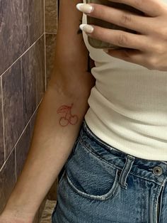 a woman with a bicycle tattoo on her arm holding a cell phone in the bathroom