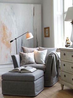 a living room filled with furniture and a lamp on top of a wooden floor next to a window