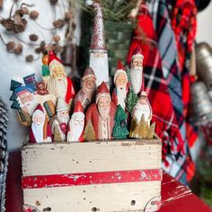 a group of gnome figurines sitting on top of a wooden box in front of a christmas tree