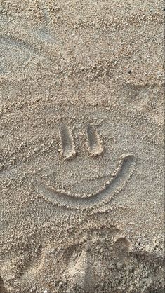 a smiley face drawn in the sand on a beach