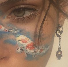 a woman's face painted with blue, red and white paint on her left eye